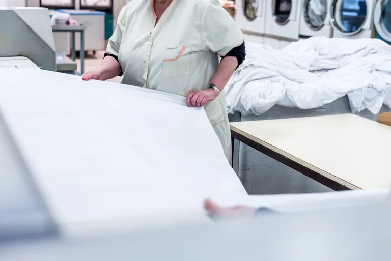 Frau faltet W&auml;sche in W&auml;scherei.