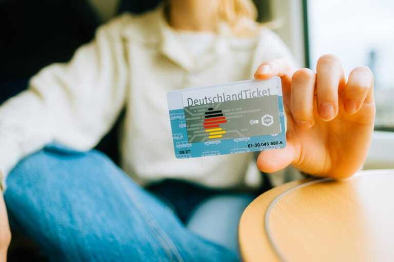 Junge Frau h&auml;lt Deutschlandticket in die Kamera.
