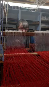 Beim Schafteinzug, dem Einf&auml;deln der hier wei&szlig;en Kettf&auml;den, passend zwischen die hier roten Schussf&auml;den, muss sich Sylvia Wiechmann gut konzentrieren.