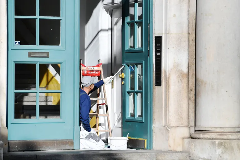 Maler,Anstreicher streicht eine Eingangstuere eines Altbaus.