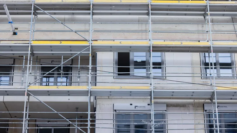 Fenster werden in einen Rohbau eines Mehrfamilienhauses mit Mietwohnungen eingebaut.