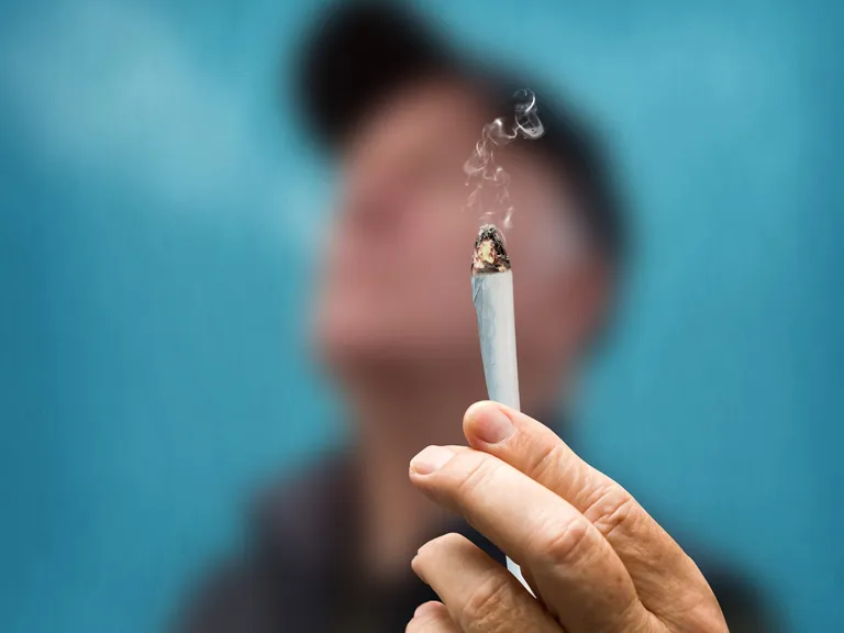 Eine Hand mit einem brennenden Joint