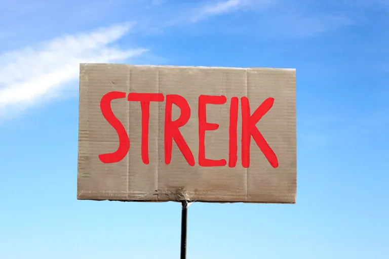 Streik-Schild vor blauem Hintergrund.