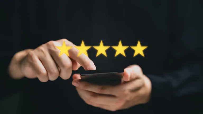 Frauenhand gibt auf Handy Sternebewertung ab.