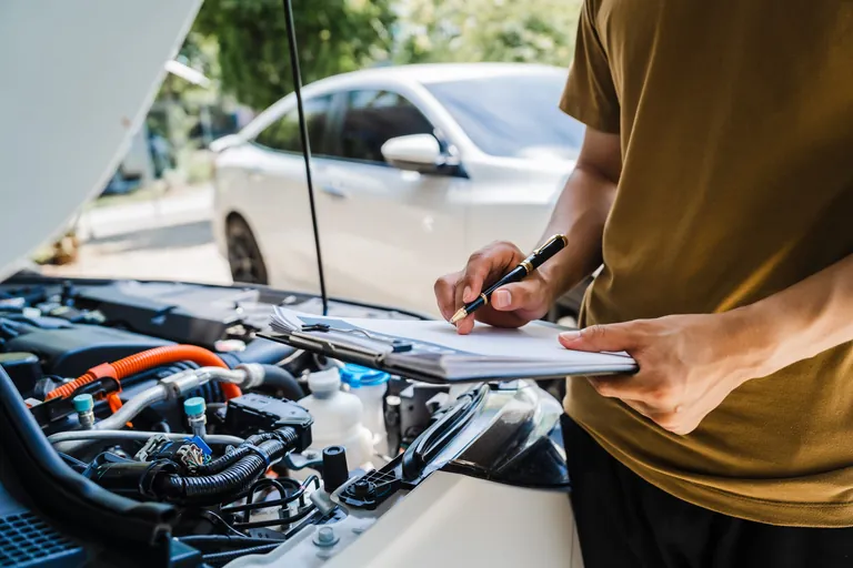 Ein Mann f&uuml;llt nach einem Autounfall ein Versicherungsformular aus.