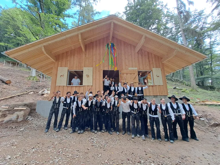 Kursteilnehmerinnen und -teilnehmer vor der fertigen H&uuml;tte 