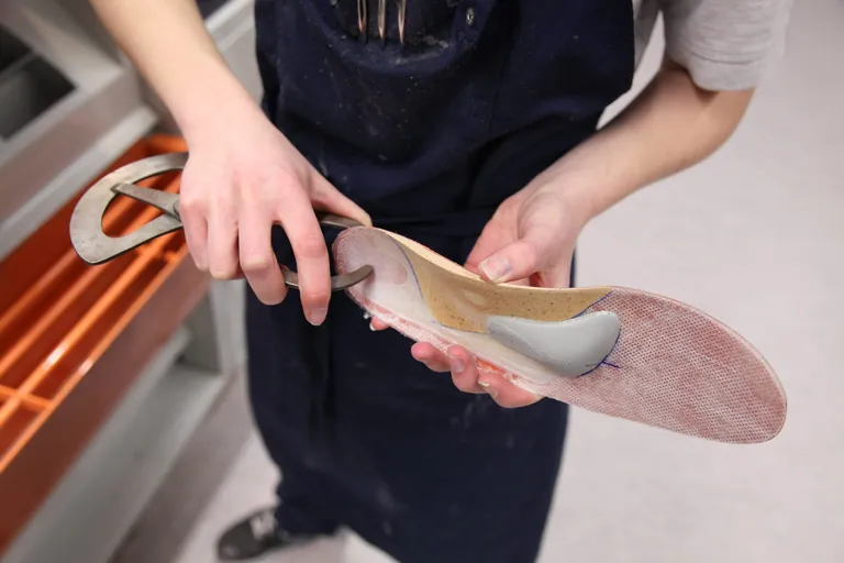 Ein Orthop&auml;die-Schuhtechniker bearbeitet eine Einlage. 