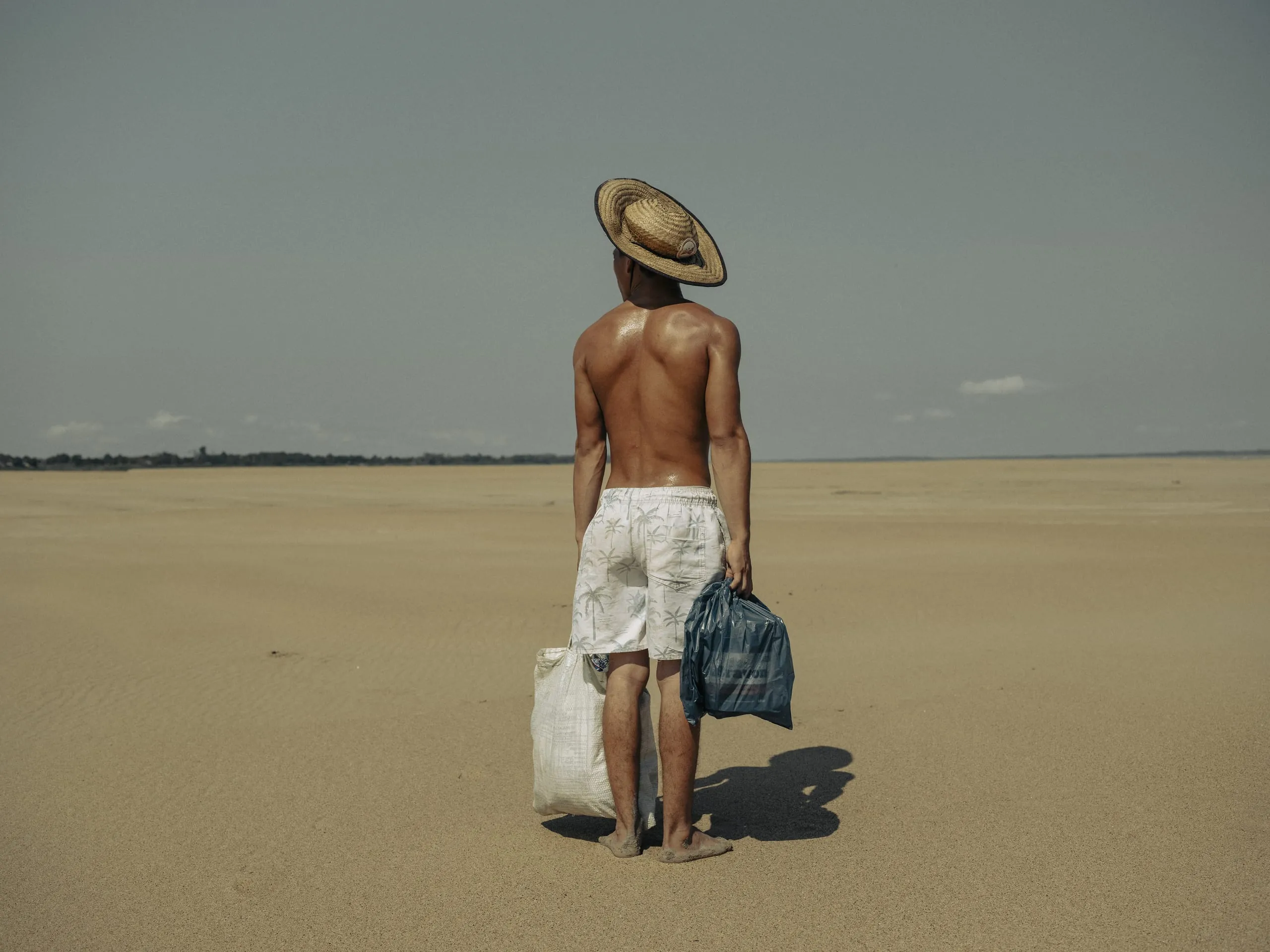 Ein junger Mann bringt seiner Mutter, die in dem Dorf Manacapuru lebt, Essen. Das Dorf war früher mit dem Boot erreichbar, aber wegen der Dürre muss er zwei Kilometer entlang des trockenen Flussbettes des Solimões-Flusses laufen, um sie zu erreichen. [Amazonas, Brasilien, 5. Oktober 2024]