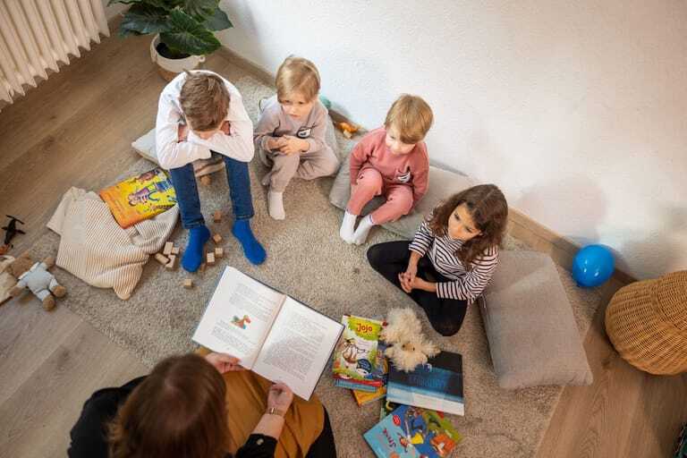Frau liest vier Kindern ein Buch vor