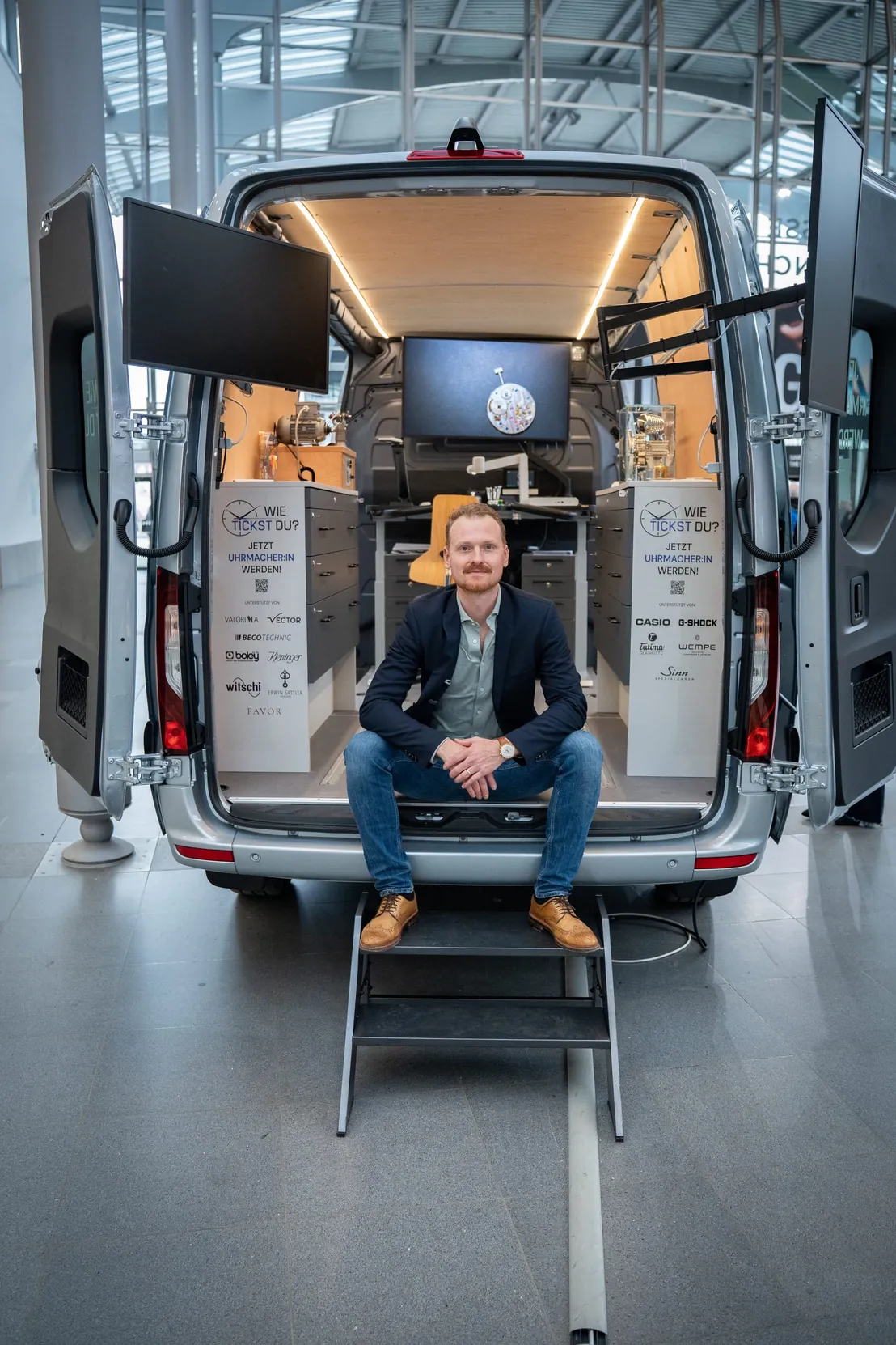 Michael Man&szlig;hardt mit Bildschirm und Sicht auf den Heckbereich des Mobils mit Bildschirmen