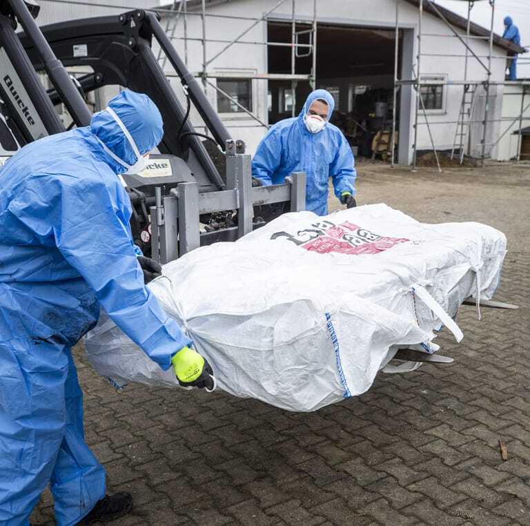Zwei Handwerker entsorgen asbesthaltige Dachplatten in Bigbags.