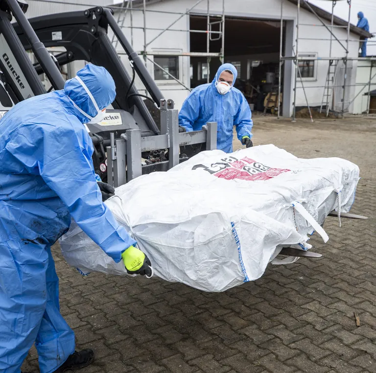 Zwei Handwerker entsorgen asbesthaltige Dachplatten in Bigbags.