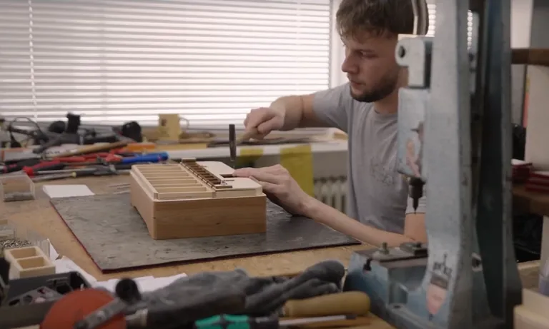Junger Mann klopft N&auml;gel in Holzst&uuml;ck