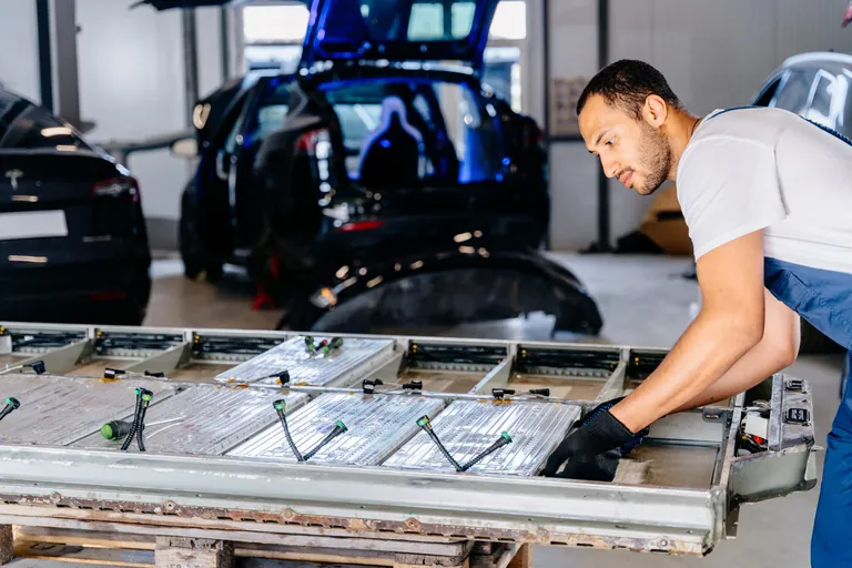 Mann repariert E-Auto in Kfz-Werkstatt