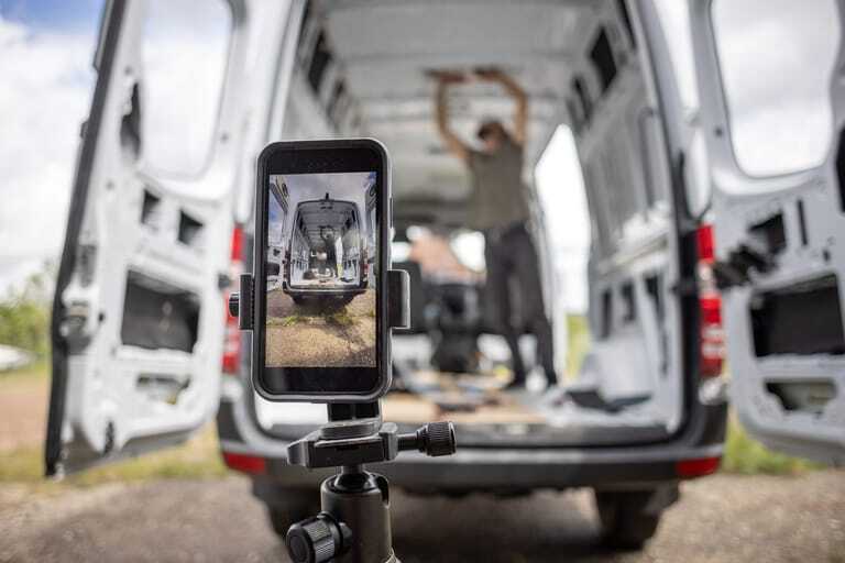 Smartphone-Stativ filmt Handwerker bei Transporter-Ausbau