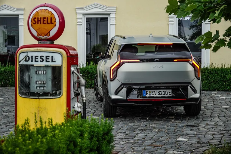 Heck des Kia EV3 vor einer historischen Dieseltanks&auml;ule