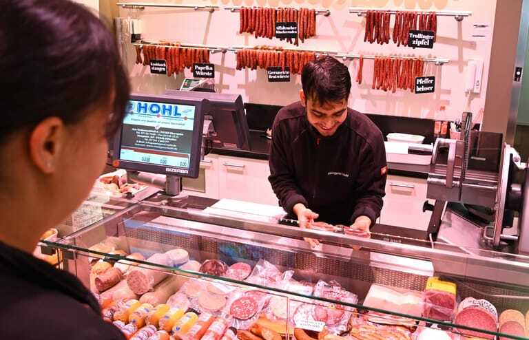 Fleischereifachverkäufer-Azubi Naved Khan bedient eine Kundin