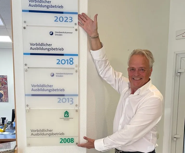 Zahntechnikermeister Torsten B&uuml;ker zeigt seine Auszeichnungen als vorbildlicher Ausbilder.