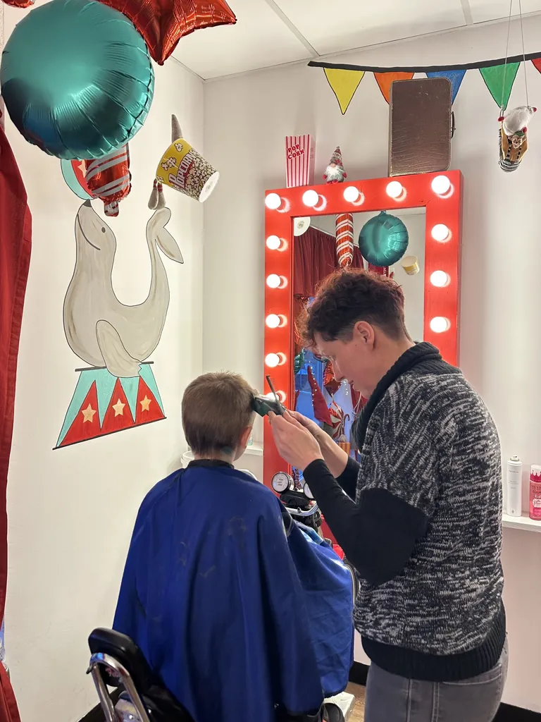 Friseurin Isabell Lef (r.) setzt bei dem neunj&auml;hrigen Julius (l.) die Haarschneidemaschine an.