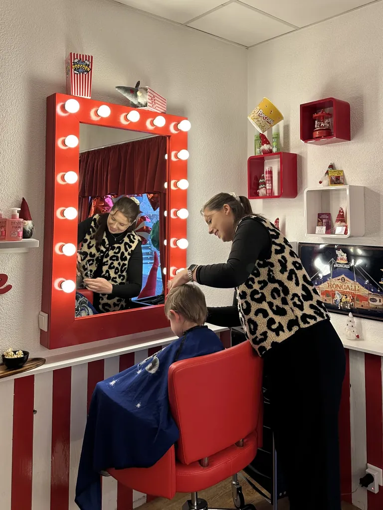 Zwischen Leuchtspiegel und Popcorn-Deko. Friseurin Lina Slepinski (r.) arbeitet mit Kamm und Schere am Haar von Jonathan (l.).