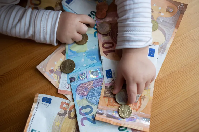 Kind greift nach Geldscheinen